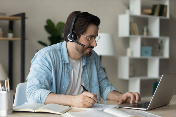 istock Man wear headset listens audio course makes notes studying online 1331313434