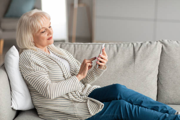 istock Mature woman using mobile phone resting on sofa 1331318073