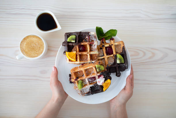 과일과 시럽으로 장식된 벨기에 와플접시를 들고 있는 여성, 커피 한 잔, 최고 전망 - waffle eating meal food and drink 뉴스 사진 이미지