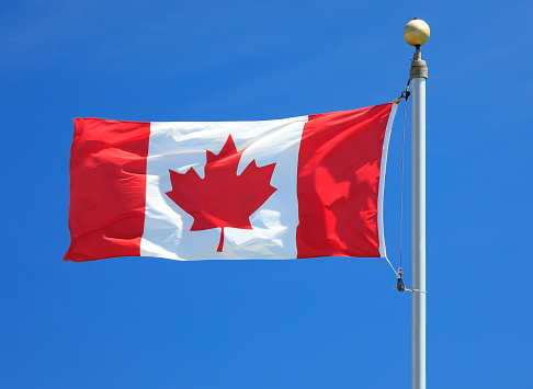 Canadian Flag waving in the wind surrounded by blue background