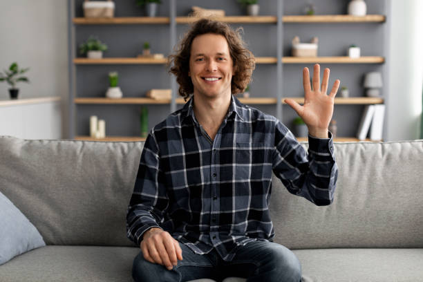 istock Positive Man Waving Hello In Greeting Gesture Sitting At Home 1331321330