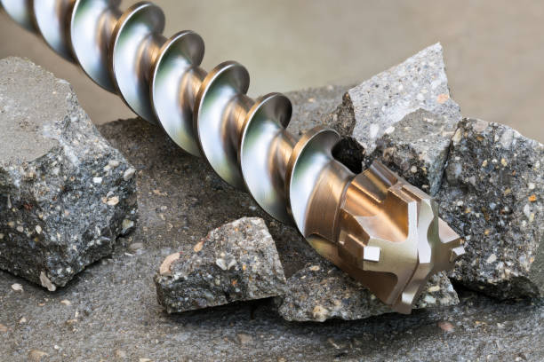 Closeup of masonry drill bit tip with carbide insert brazed to steel on a broken concrete Beautiful still life of spiral fluted tool with sharp metal cutters. Rebar resistant. Drilling holes in hard building materials tungsten metal stock pictures, royalty-free photos & images
