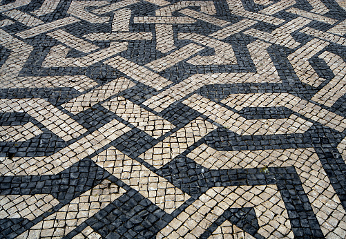 Lisbon, Portugal: labyrinthine black and white pattern with sinouos lines and knots of a traditional Portuguese pavement, a form of cobblestone pavement known as 'calçada' - made using limestone and basalt cubes.