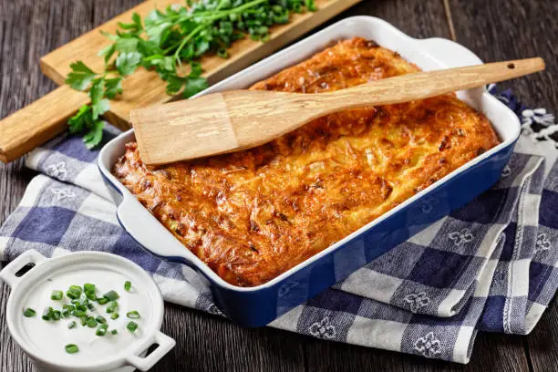 savory potato kugel, baked pudding or casserole of grated potato in a baking dish on a wooden table, jewish holiday recipe, close-up
