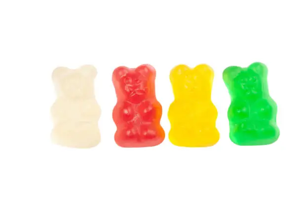 Photo of Multicolored gummy bears arranged in line isolated on white