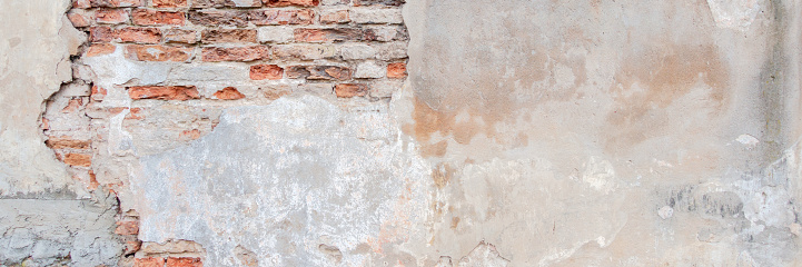 Old grungy red brick wall with peeled stucco background. Vintage retro plaster wall with dirty cracked scratched texture background