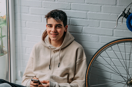 young teenager at home with mobile phone and bicycle