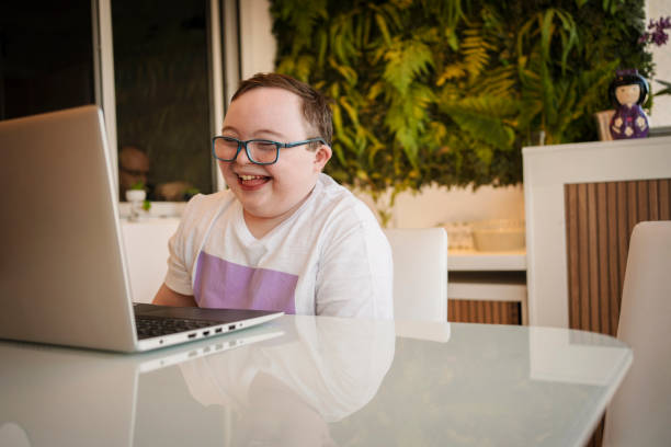 Boy with down syndrome in homeschooling. Distance learning concept. stock photo
