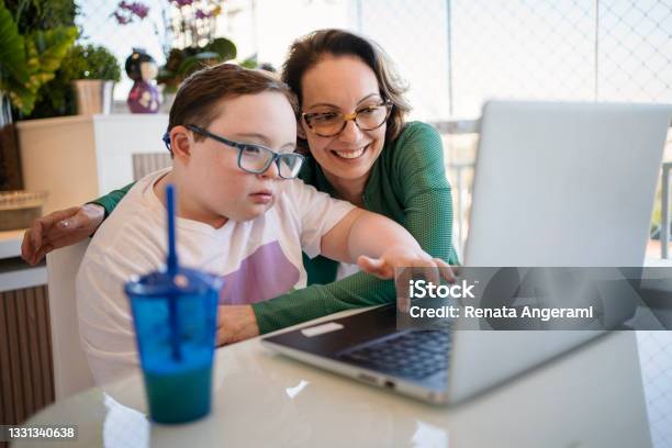 Mother Helping Son With Down Syndrome In Homeschooling Distance Learning Concept-foton och fler bilder på Funktionsnedsättning