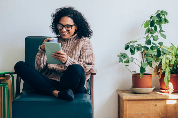 Cheerful Woman Drinking Coffee and Using a Digital Tablet