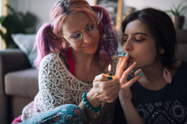 jovem casal lgbtqia fumando maconha em casa - lesbian love sexual issues two people - fotografias e filmes do acervo