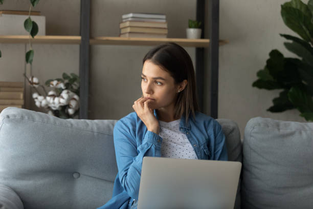 istock Pensive woman sit on sofa with laptop 1331346482