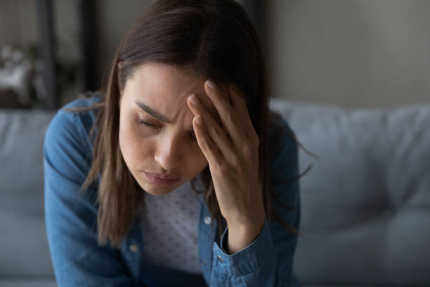 istock Closeup sad woman sit on sofa touch aching head 1331346493