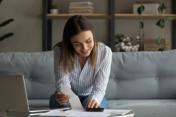Smiling woman manage personal finances makes calculations on calculator