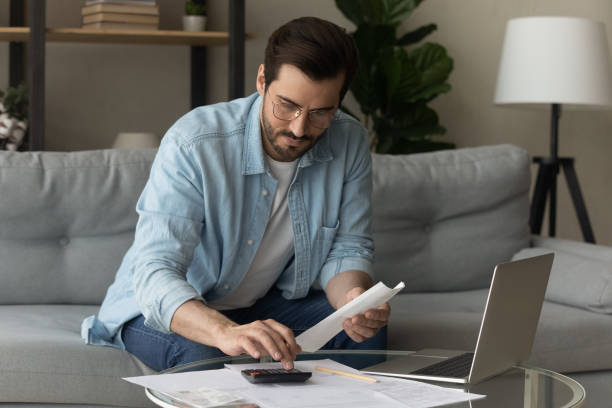 istock Serious man calculates expenses working sit on sofa at home 1331346508