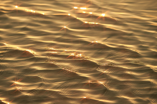 Texture of glitter water and soft waves. sparkling in water - background. sea water with sun glare and ripple. Powerful and peaceful nature concept.Texture of glitter water and soft waves. sparkling in water - background. sea water with sun glare and ripple. Powerful and peaceful nature concept.