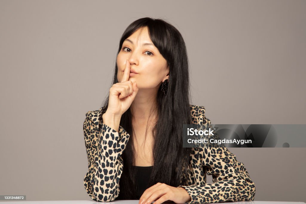 Young woman with finger on lips Keep it secret, portrait, Studio shot Human Lips Stock Photo
