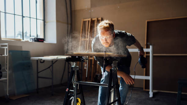 carpenter blowing dust from wooden plank - carpenter carpentry craft skill imagens e fotografias de stock