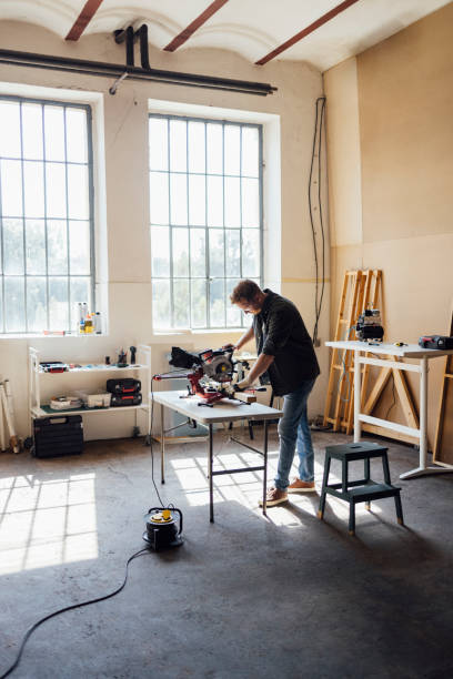 istock Carpenter Cutting Wood on a Mitre Saw at his Workshop 1331350659