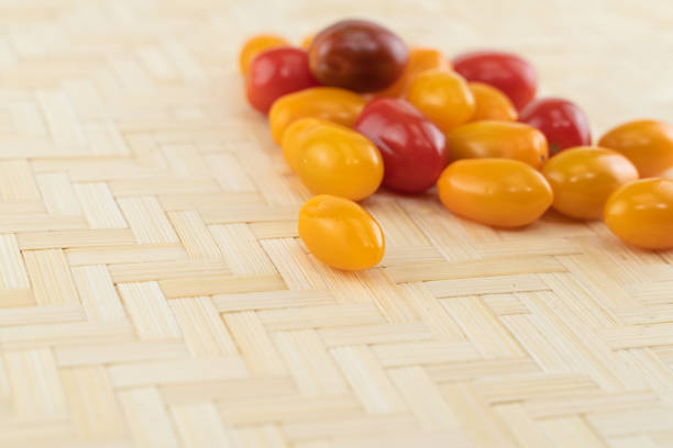 yellow and red cherry tomatoes on a light wooden background with copy space