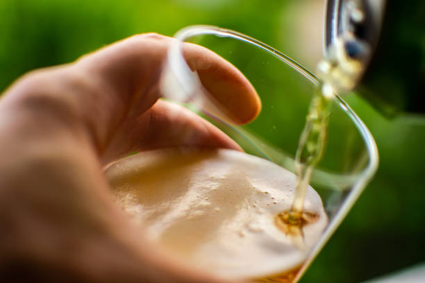 versamento di birra fredda e rinfrescante in vetro con schiuma, bevande, alcol, concetto di festa. prodotto di qualità preparato e realizzato su sfondo colorato e sfocato. - half light foto e immagini stock