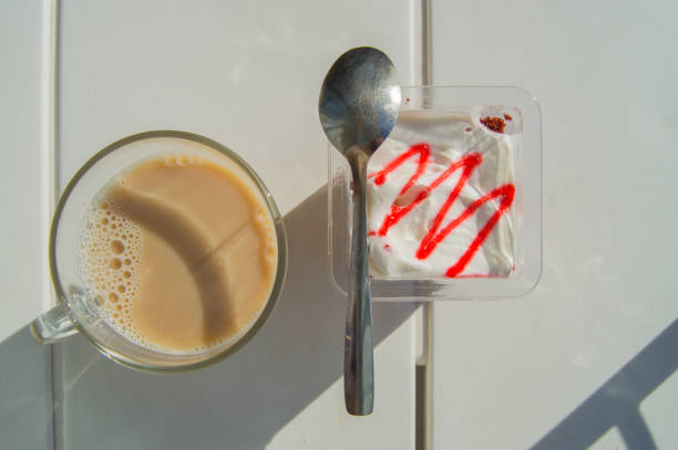 diätfrühstück mit kaffee latte und joghurt mit erdbeermarmelade, blick auf den tisch mit sonnenlicht und schatten - snack coffee instant coffee cappuccino stock-fotos und bilder