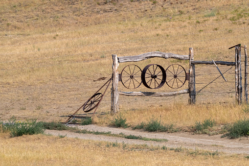 Antique ranch fence decorations with steel wheels in rural ranch lands on Montana prairies. John Morrison - Photographer