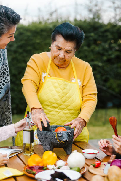 lateinische großmutter und enkelin, tochter kocht mexikanisches essen zu hause, drei generationen von frauen in mexiko - mexican culture food salsa mexican cuisine stock-fotos und bilder