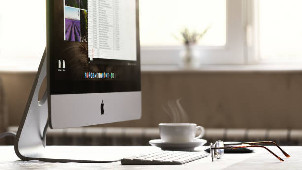 компьютер imac и очки на столе - apple computers стоковые фото и изображения