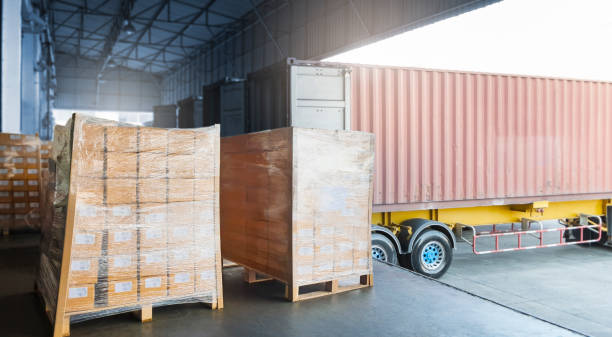 istock Stacked of Package Boxes on Pallets Load with Cargo Container. Trailer Truck Parked Loading at Dock Warehouse. Delivery. Shipping Warehouse Logistics. Cargo Freight Truck Transportation. 1331397369