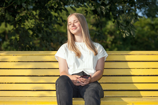 Outdoors portrait of 15 year old blonde teen girl with long hair in white t-shirt