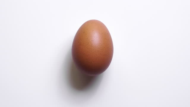 4k stop motion : Top view of spinning egg on white background