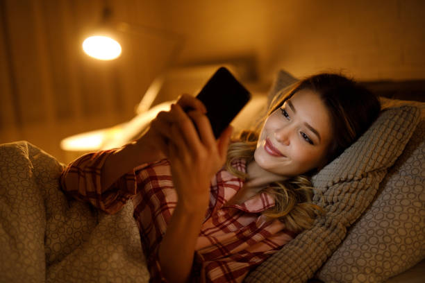 istock Beautiful young woman using mobile phone in bed 1331401202