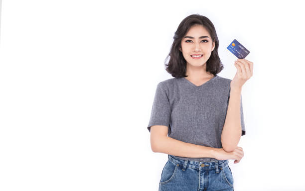 portrait of young smiling beautiful asian woman presenting credit card in hand showing trust and confidence making payment, online shopping financial account telemarketing e-commerce concept - japanese ethnicity women asian and indian ethnicities smiling imagens e fotografias de stock