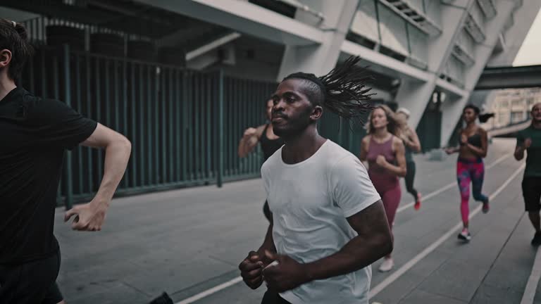 African American man and his like-minded friends dressed in a portable uniform have a group running training. Black man and his team of athletes running through the stadium