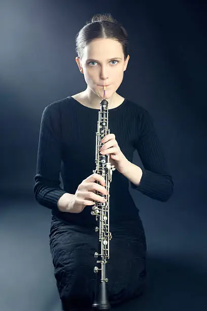 Young musician oboist woman playing oboe. It's not clarinet, it's oboe! It is first musical instrument of classical symphony orchestra.