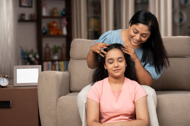 мама делает масляный массаж головы дочери дома - massaging head massage ethnic beauty стоковые фото и изображения