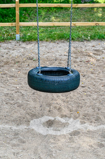Funny kid boy having fun with chain swing on outdoor playground. child swinging on warm sunny spring or autumn day. Active leisure with kids. Selective focus, no face of kid