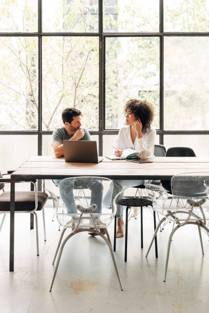 istock Young multiracial people interacting in bright co working loft office with big window. Coworkers concept. Vertical image. 1331412506