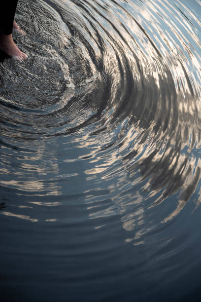 istock Feet make serene concentric circle ripples on glassy pond water surface with sky reflection 1331412642