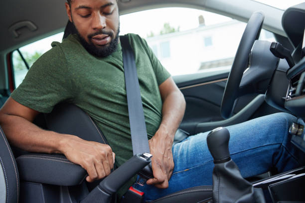 male driver in car fastening seatbelt before setting off on journey - fastening imagens e fotografias de stock