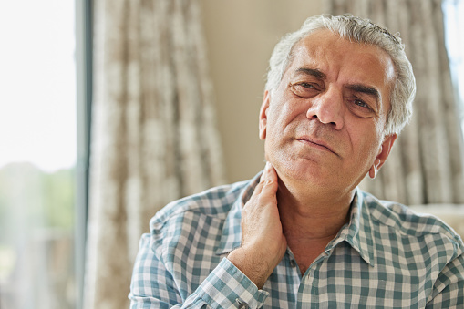 Mature Man At Home Suffering From Muscle Pain Or Ache In Neck