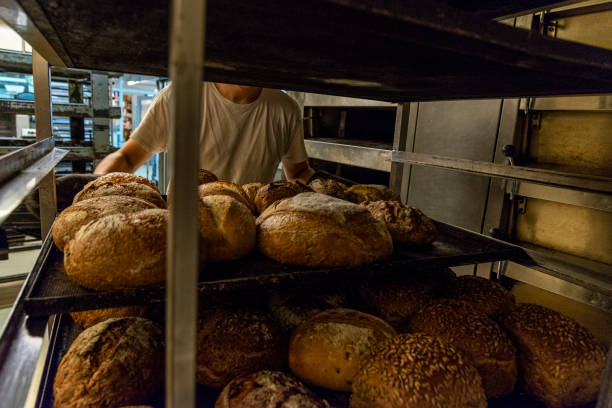 istock Baker taking bread out of oven 1331416268