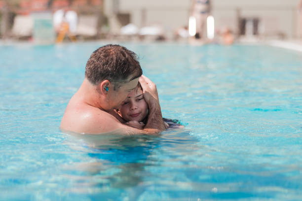 istock Man comforting his scared daughter at swimming pool 1331425468