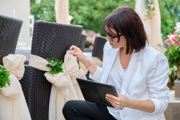 Woman professional decorator with digital tablet working outdoors decorating ceremony