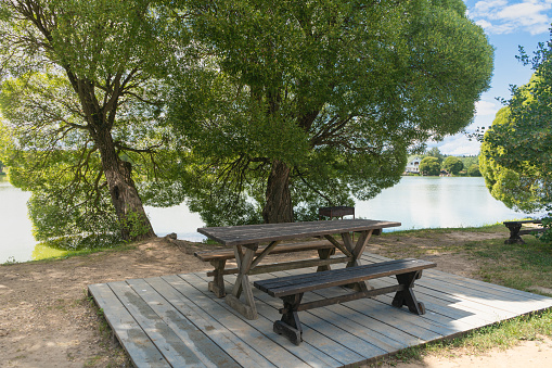 Empty picnic bench by the roadside next to the pond. tourism concept