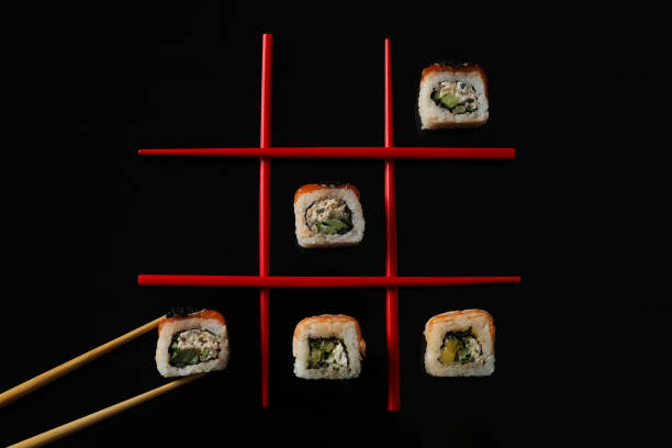 istock Tic-tac-toe game made with delicious sushi rolls and chopsticks on black background, flat lay 1331428021