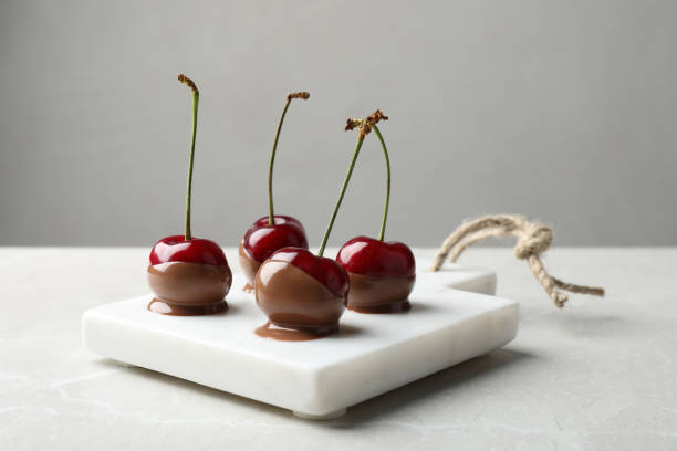 Sweet chocolate dipped cherries on white table Sweet chocolate dipped cherries on white table Chocolate Dipped stock pictures, royalty-free photos & images