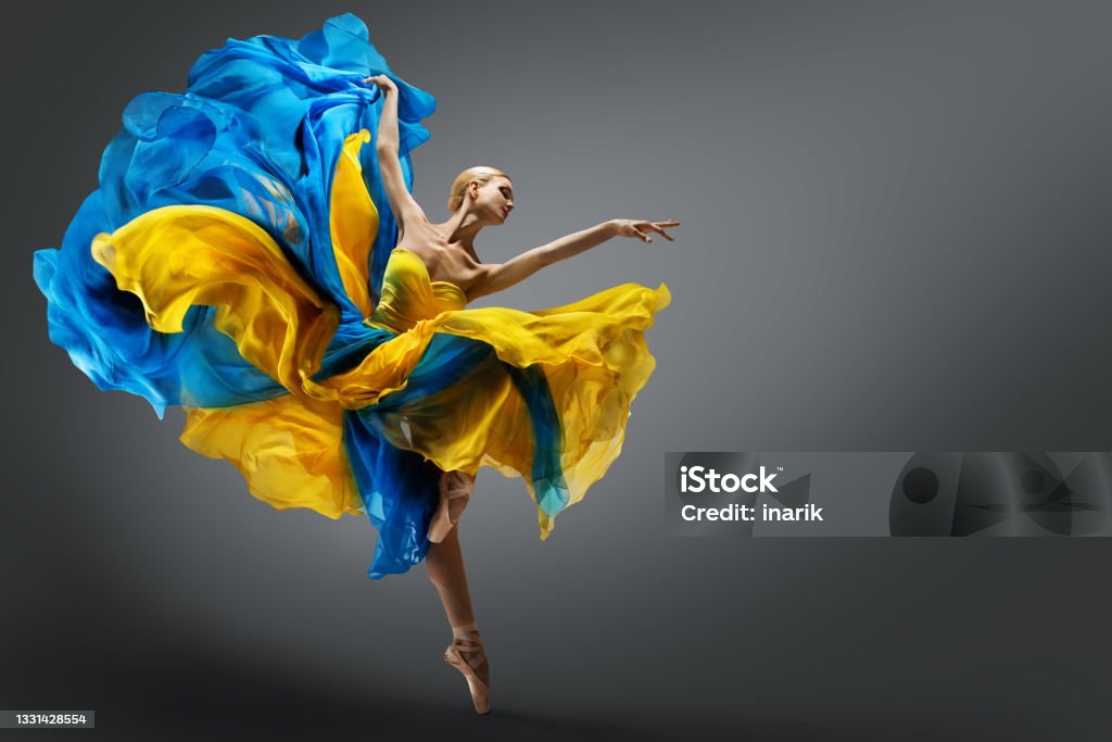 Beautiful Woman Ballet Dancer Jumping in Air in Colorful Fluttering Dress. Graceful Ballerina Dancing in Yellow Blue Gown over Gray Studio Background Beautiful Woman Ballet Dancer Jumping in Air in Colorful Fluttering Dress. Graceful Ballerina Dancing in Yellow Blue Gown over Gray Studio Background. Dynamic Motion Dance Dancing Stock Photo