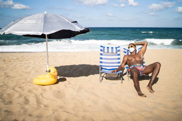 ein einsamer mann, der sich am schönen strand mit gesichtsmaske sonnt - beach men isolated tourist stock-fotos und bilder